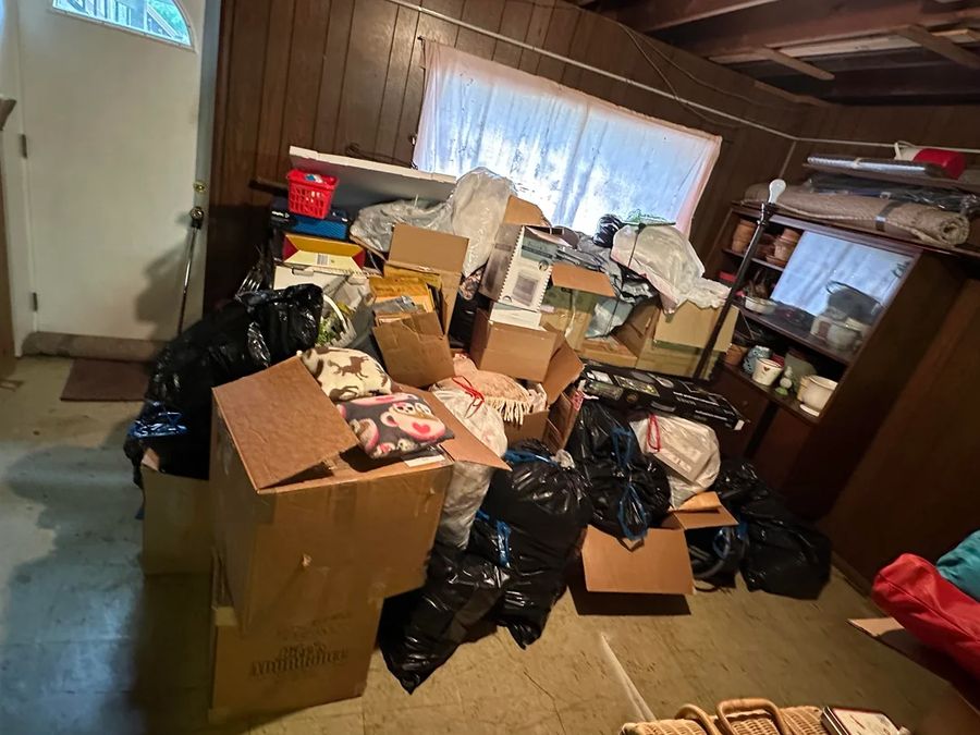 Basement room piled with boxes and bags before junk removal in Queens